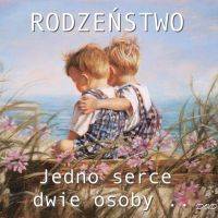 Dwóch chłopców w ogrodniczkach przytula się na ławce nad morzem, otoczeni różowymi kwiatami; czuła więź rodzeństwa